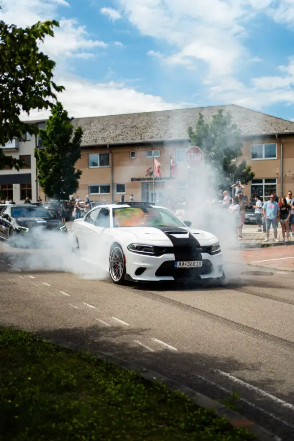 Biely Dodge Charger pri burnoute pred divákmi